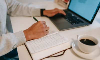 freelancer browsing laptop and taking notes in notebook during work employee laptop