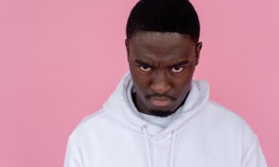 angry black man in hoodie against light pink background